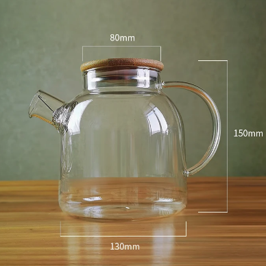 Eine transparente Borosilikatglas Teekanne mit Holzdeckel, abgerundetem Henkel und Ausguss, neben Maßangaben in Millimetern.
