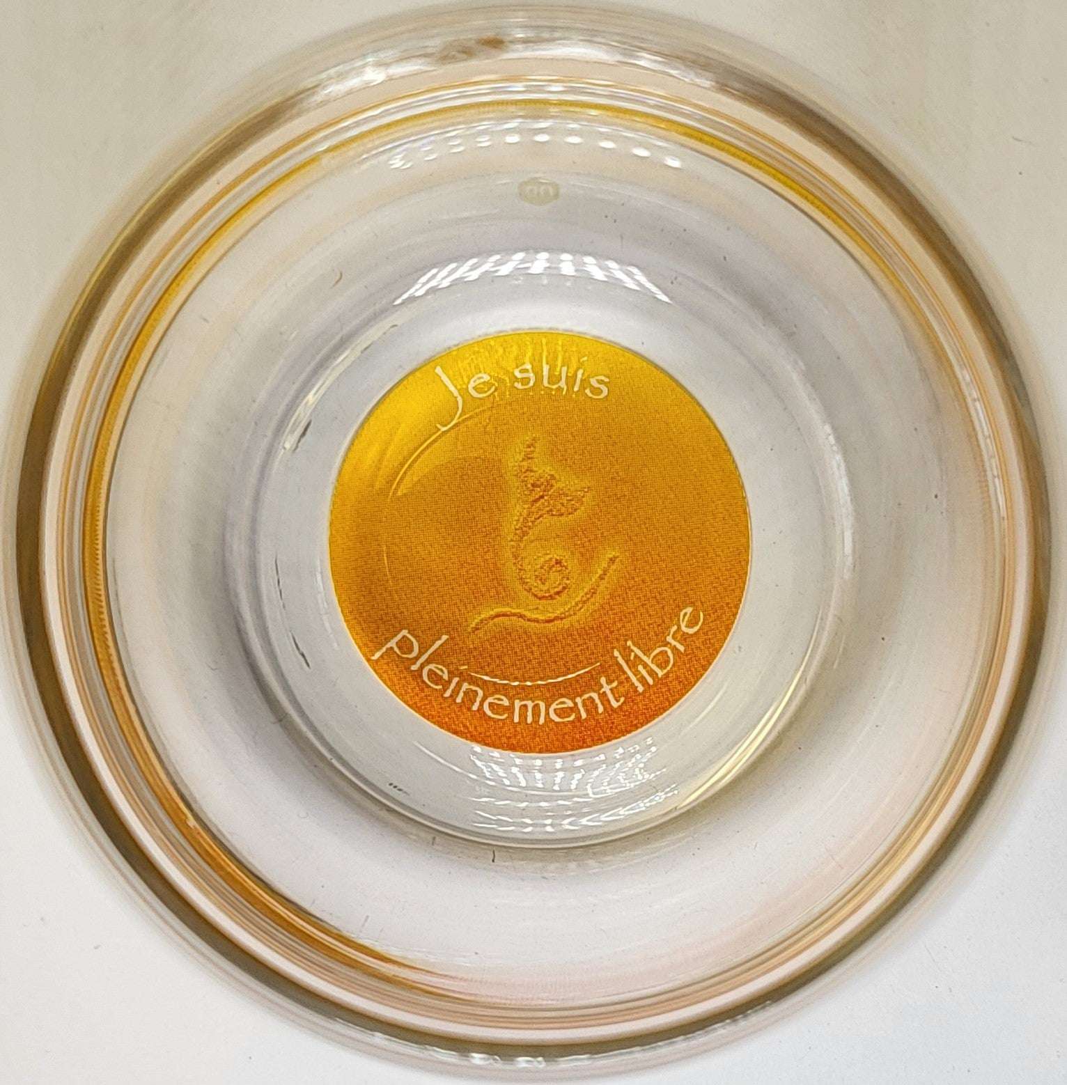 Ein stilvolles, transparentes Glas Mythos Becher mit goldgelbem Boden, französischer Affirmation "Je suis pleinement libre".