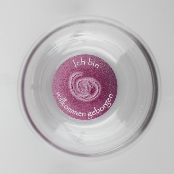 Ein klarer Mythos Becher mit lila Boden, darauf steht die Affirmation „Ich bin vollkommen geborgen“ und eine Spirale.