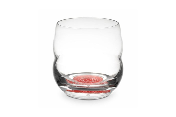 Ein einzelnes klares Glas mit gewölbter Form, am Glasboden rotes Chakra-Symbol und feine weiße Linienverzierung erkennbar.