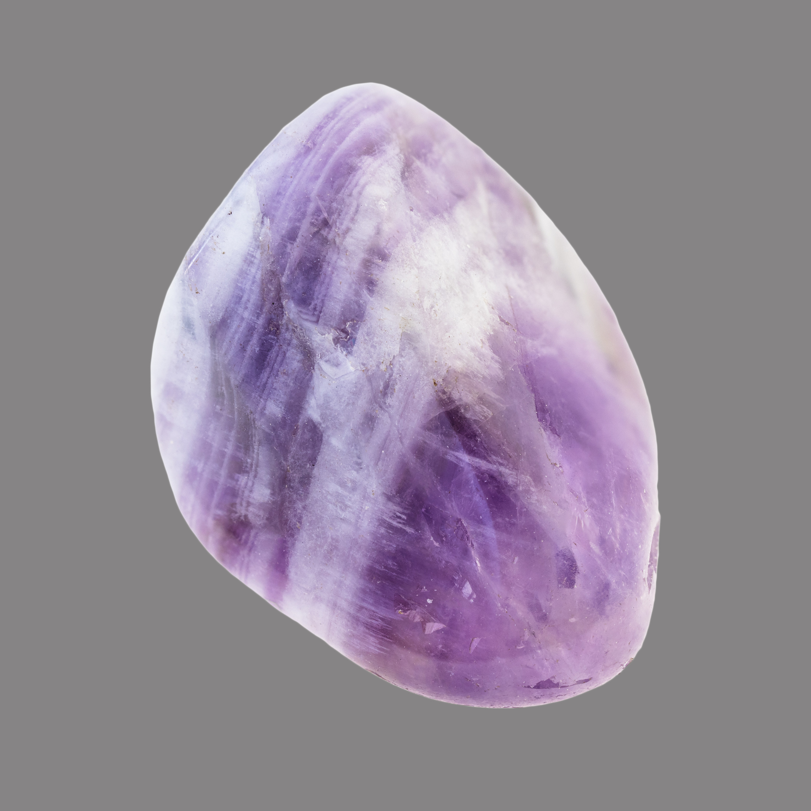 Ein polierter Amethyststein mit violetten und weißen Bändern, leicht durchscheinend und oval, vor grauem Hintergrund.