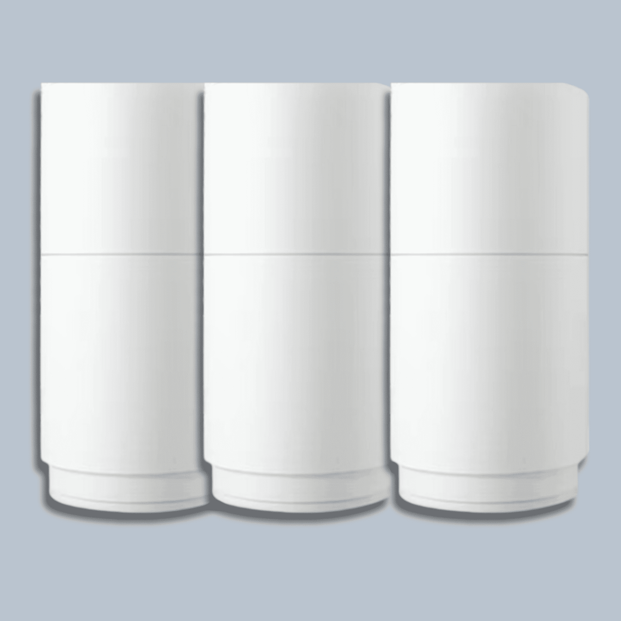 Drei weiße, zylindrische Filtergehäuse stehen nebeneinander vor grauem Hintergrund, schlichtes und modernes Design.