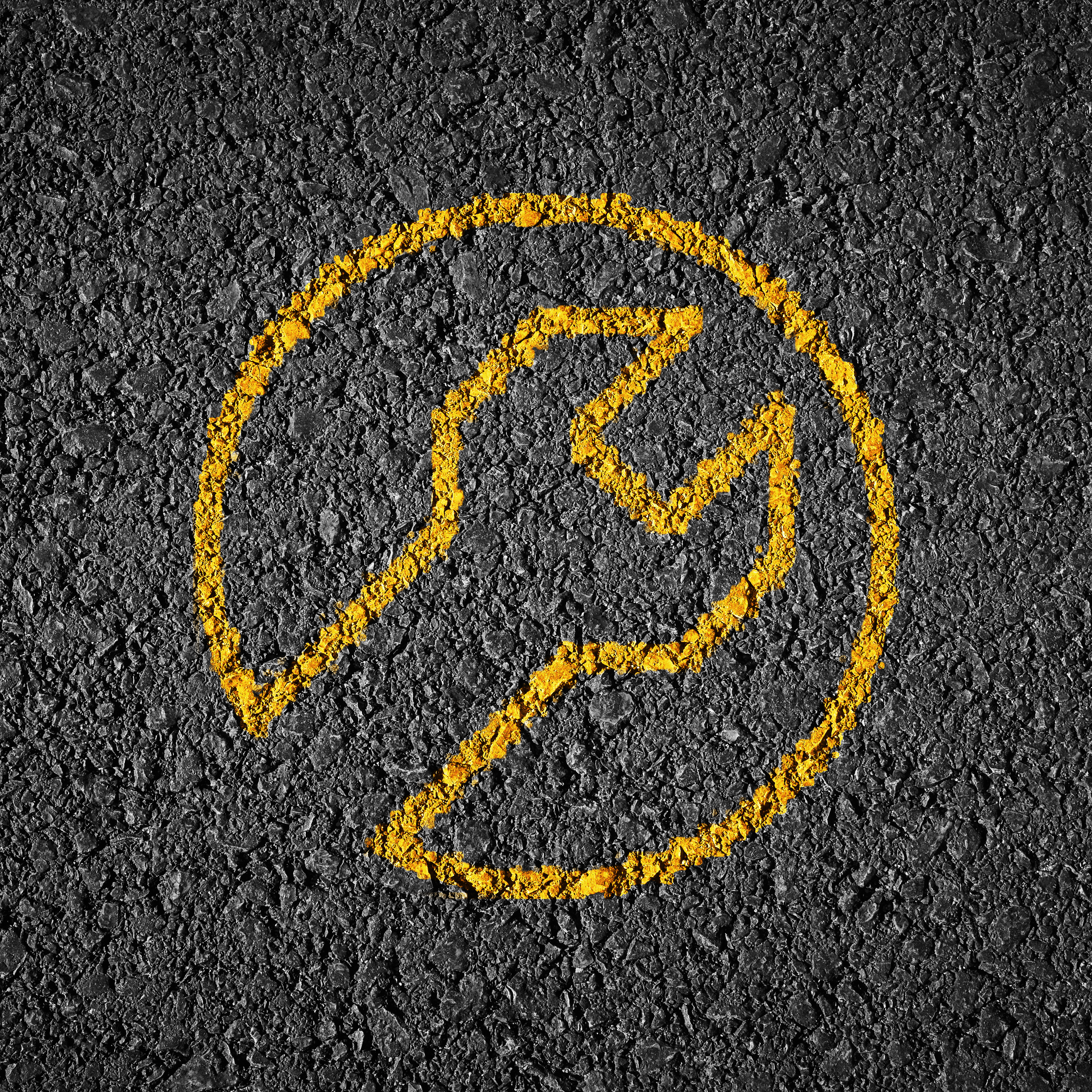 Auf grobkörnigem Asphalt ist ein gelbes Kreissymbol mit einem Schraubenschlüssel in der Mitte deutlich aufgemalt.