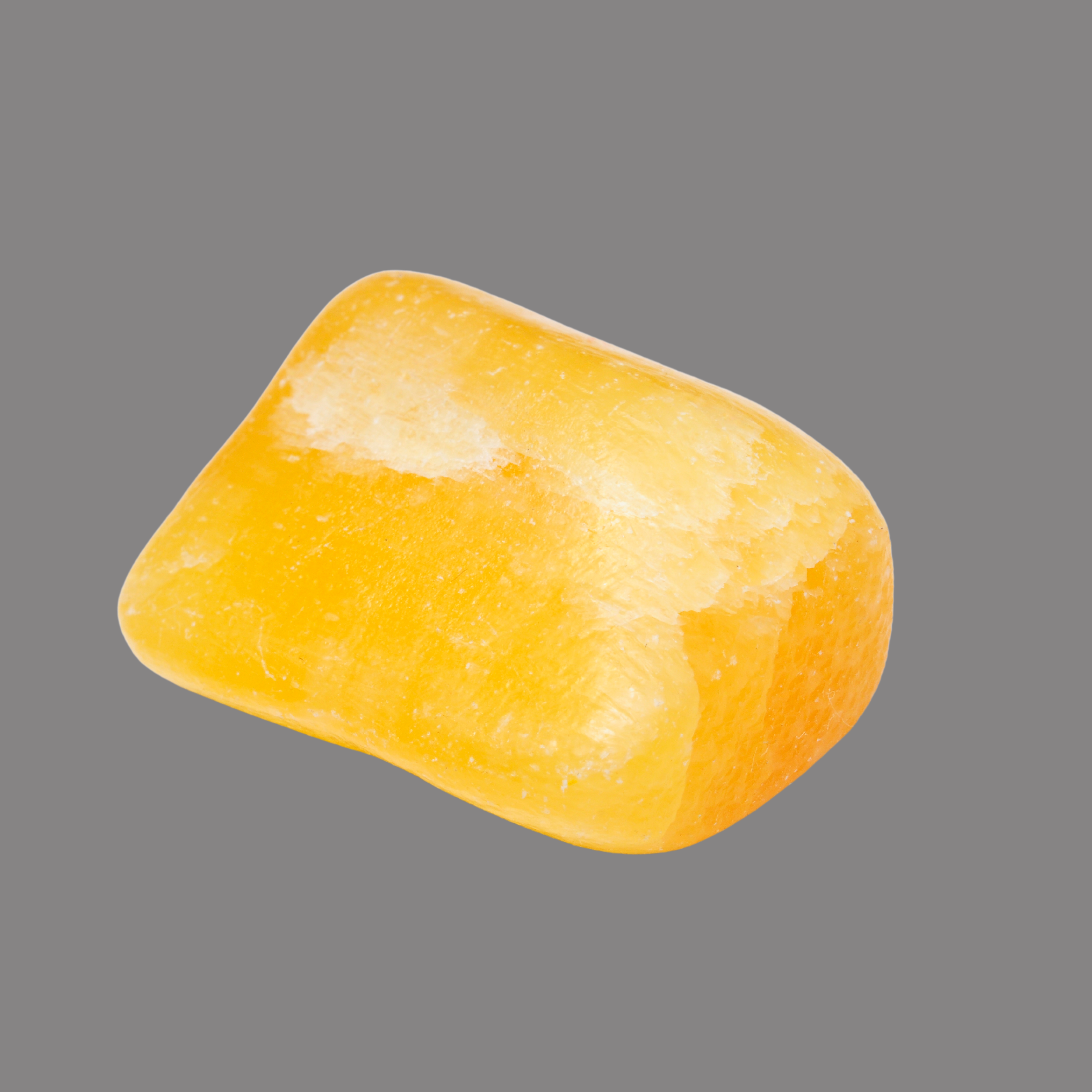 Ein einzelner, rechteckiger, gelblich glänzender Stein mit glatter, polierter Oberfläche und weißen Schimmerflecken.